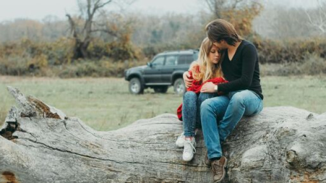 Coppia innamorata seduta su un tronco- &copy; Pexels