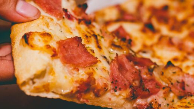 Una fetta di pizza che viene sollevata &copy; Pexels