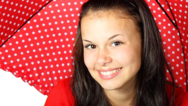 Ragazza sorridente con ombrellino rosso a pois - &copy; Pixabay.