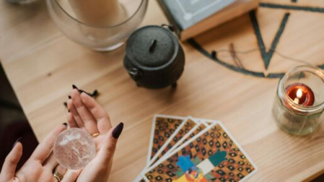 Mani che leggono i tarocchi e sfera- &copy; Pexels.