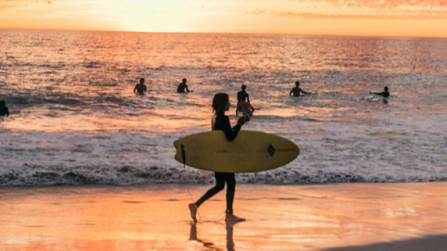 Donna con tavola da surf al mare - &copy; Pexels