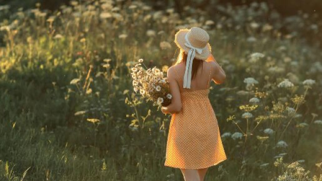 Ragazza di spalle con in mano dei fiori &copy; Pexels