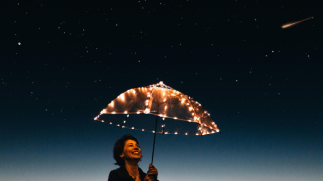 Donna con un ombrello sotto un cielo stellato &copy; Pixabay
