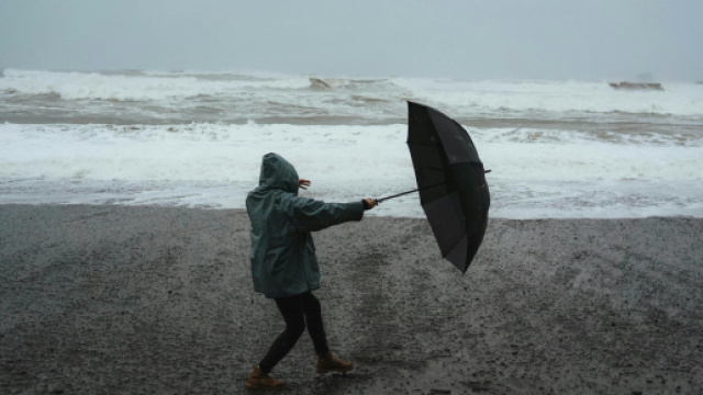 Uomo con ombrello e mare in tempesta - &copy; Pexels.