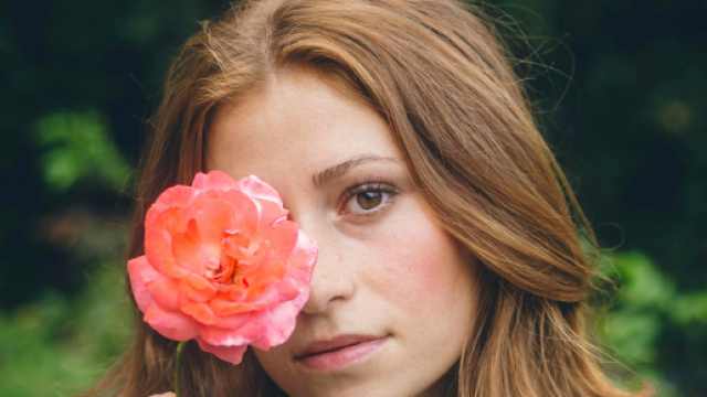 Ragazza che nasconde il viso con una rosa- &copy; Pexels.
