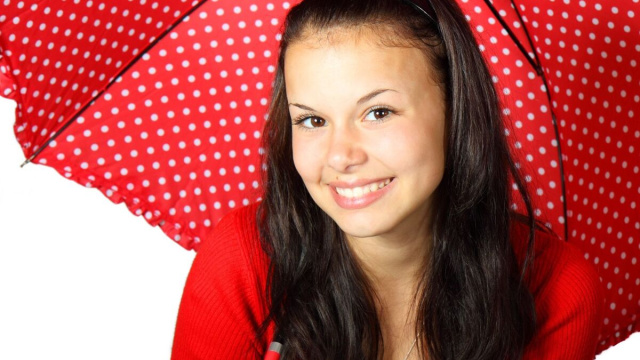 Donna sorridente con ombrellino rosso a pois - &copy; Pixabay.