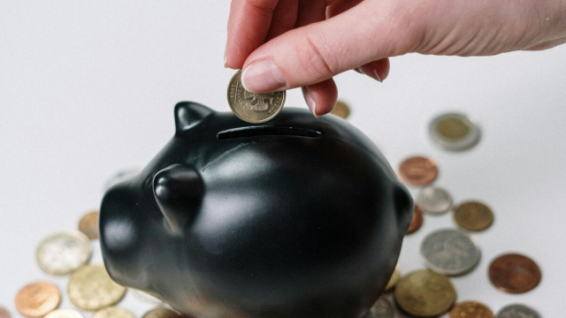 Mano che mette monete nel salvadanaio - &copy; Pexels.