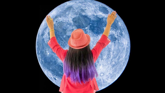 Una ragazza col cappello abbraccia una grande Luna &copy; Pixabay.