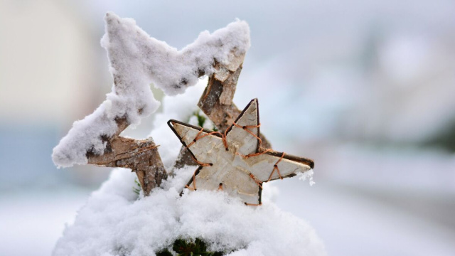 Due decorazioni a forma di stella in legno parzialmente coperte di neve &copy; Pixabay.