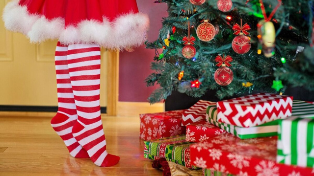 Gambe di una bambina vicino all&rsquo;albero di Natale e ai regali &copy; Pixabay.