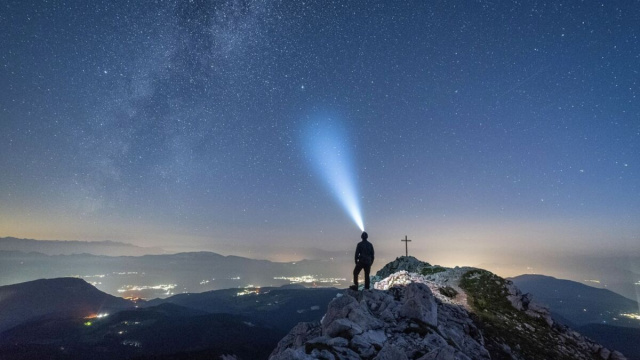 Una persona su una montagna sotto le stelle - pixabay.com