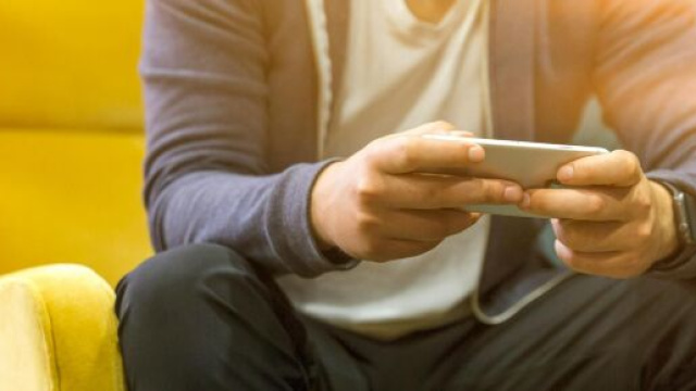 Un uomo che regge in mano uno smartphone - &copy; Pexels.com