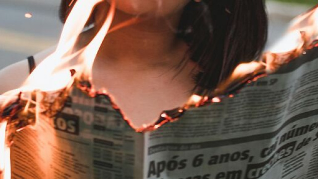 Donna che legge un giornale che brucia &copy; Pexels