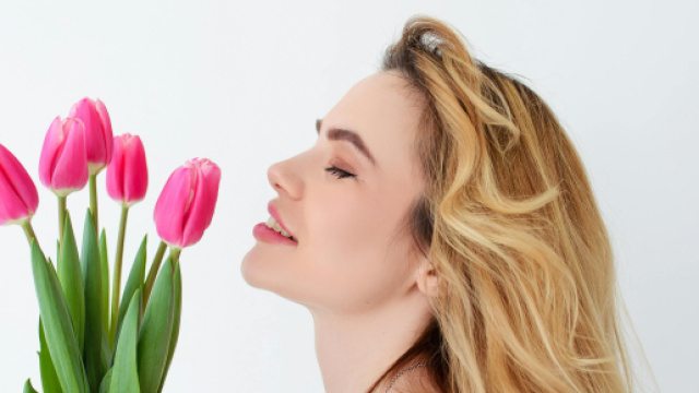 Una donna che annusa dei fiori, simbolo di primavera &copy; Immagine Pexels
