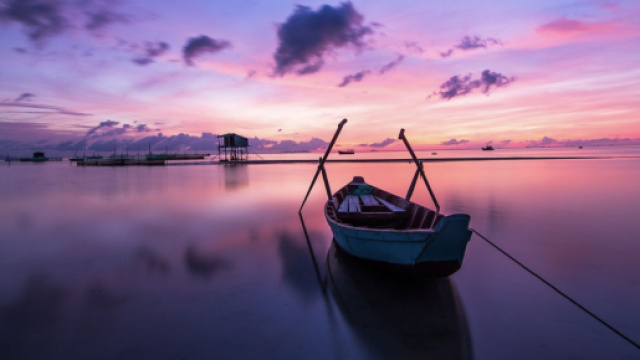 Barca in mezzo al mare al tramonto - pixabay.com.
