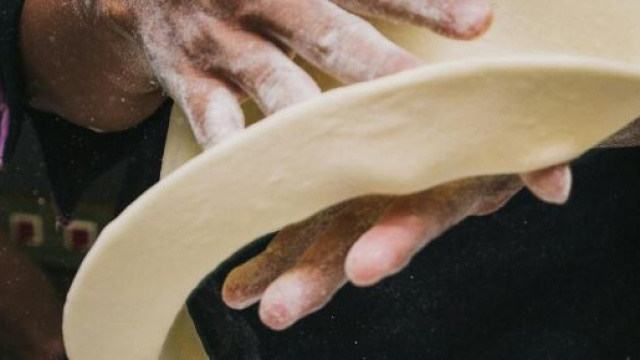 Mani che preparano una pizza &copy; Pexels.com