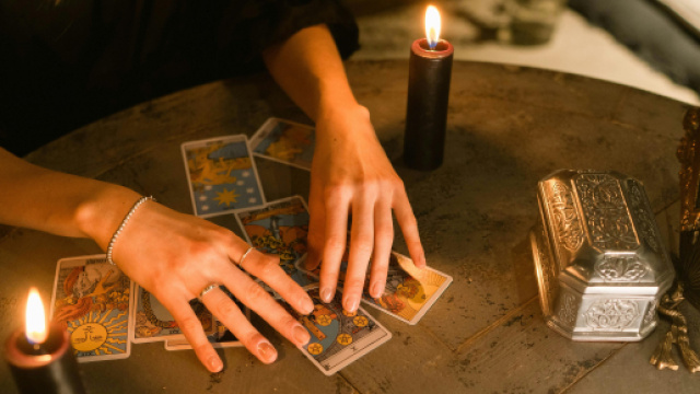 Mani che leggono i tarocchi con candele- &copy; Pexels