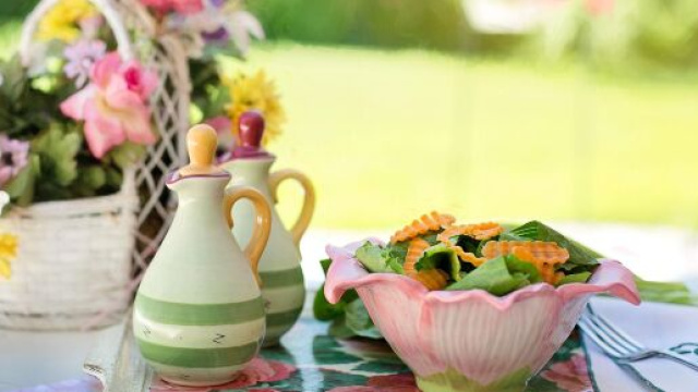 Tavolo all&rsquo;aperto con centrotavola floreale, olio, aceto e insalata fresca &ndash; &copy; Pixabay.