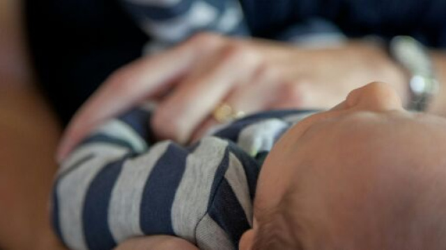 Un neonato in braccio al genitore &copy; Pexels.com