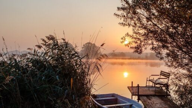 Lago, tramonto e una barchetta sul molo &copy; Pixabay.
