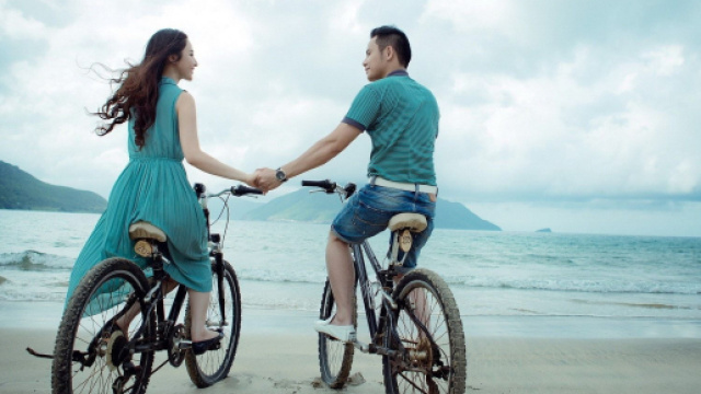 Coppia innamorata con le biciclette in riva al mare - &copy; Pixabay IA.