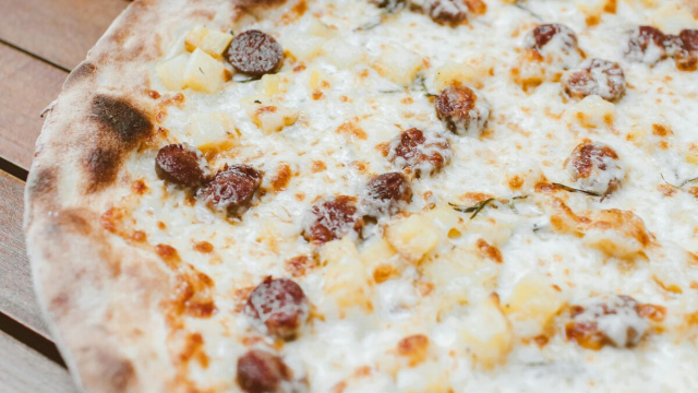 La foto di una pizza con atate e salsicce.