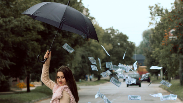 Ragazza che si ripara con ombrello dalla pioggia di banconote-&copy; Pexels
